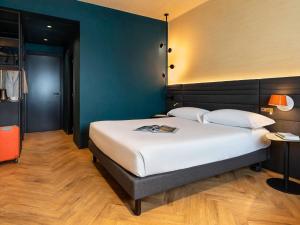 a bedroom with a large white bed and a blue wall at Novotel Caserta Sud in Caserta