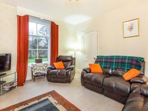 a living room with leather furniture and a television at Isla Bank Cottage in Keith
