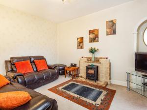 a living room with leather furniture and a fireplace at Isla Bank Cottage in Keith