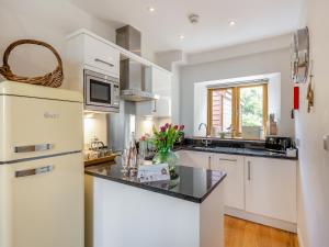 Una cocina con gabinetes blancos y un refrigerador blanco. en Toffee Apple, en Hemborough Post 32 fotos más