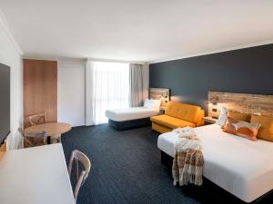 a hotel room with two beds and a couch at ibis Styles Orange in Orange