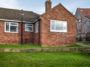 una casa de ladrillo con ventanas blancas en un patio en Sarah's Seaside Bliss, en Cromer