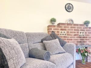 a gray couch with pillows in a living room at The Old Cook House in Winchester