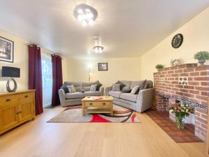 a living room with two couches and a brick fireplace at The Old Cook House in Winchester +25 photos