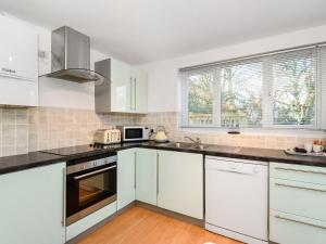 a kitchen with white cabinets and white appliances at Low Tide in Looe