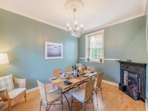 ein Esszimmer mit Tisch und Stühlen und einem Kamin in der Unterkunft Millhouse Cottage in Bamburgh