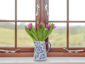 a blue and white vase with purple flowers in a window at Spire View in Redlynch