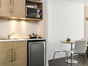 a kitchen with a table and chairs and a microwave at Aparthotel Adagio Access Paris Reuilly in Paris +26 photos