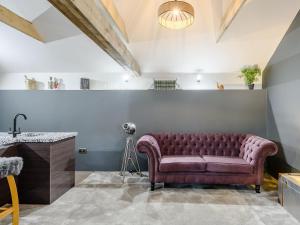 a purple couch in a room with a camera at 1 Lamb Barn in Saint Osyth