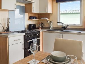 a kitchen with a table and a stove and a sink at Regal Lodge in Plumbland +11 photos