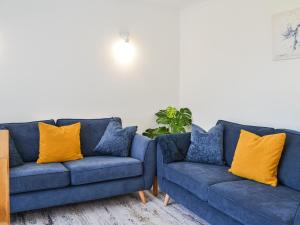two blue couches in a living room with yellow pillows at Driftwood Cottage in Sewerby
