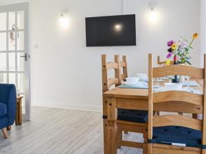 a dining room with a table and a tv at Driftwood Cottage in Sewerby