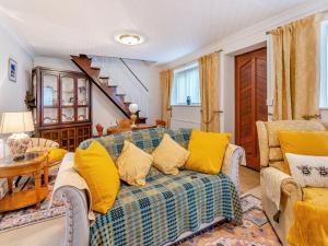 a living room with a blue couch and yellow pillows at Pant Glas Cottage in Pontardawe