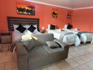 韦尔科姆Acama Guest House的一间酒店房间，配有两张床和一张沙发