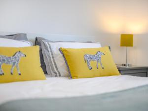 a bed with two yellow pillows with horse cushions at Willow Cottage in Stonham Aspall