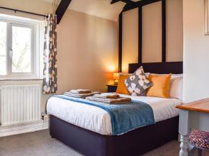 ein Schlafzimmer mit einem Bett mit orangefarbenen Kissen und einem Fenster in der Unterkunft The Cottage - Uk35177 in Abbots Bickington + 9 Fotos