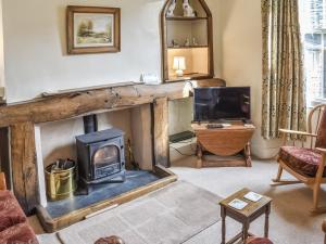 a living room with a fireplace and a tv at Yew Tree Cottage in Windermere
