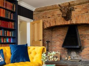a living room with a yellow couch in front of a brick fireplace at Killerby Old Hall - Uk47711 in Cayton
