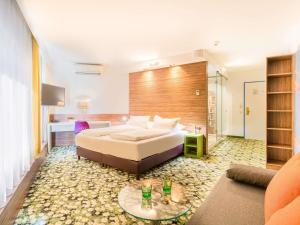 a hotel room with a bed and a living room at Ibis Styles Wien City in Vienna