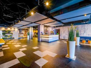a large room with a lobby with a table and chairs at Ibis Styles Regensburg in Regensburg