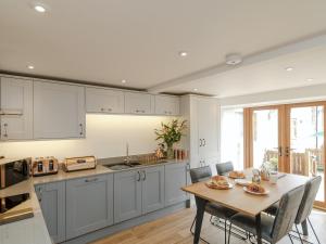 una cocina con mesa y sillas y una cocina con armarios blancos. en The Forge, en Roxby