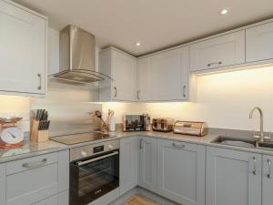 Una cocina blanca con gabinetes y electrodomésticos blancos. en The Forge, en Roxby