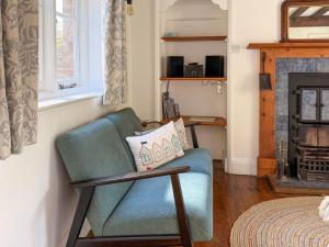 a living room with a blue chair and a fireplace at Forge Cottage in Stiffkey