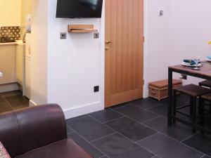 a living room with a table and a television on a wall at Bwthyn Y Celyn in Conwy