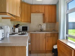 a kitchen with wooden cabinets and a sink at Old Town Cove - Uk47724 in St Merryn