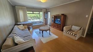 a living room with a couch and chairs and a television at Volgens Plan Family Holiday Home in Little Brak River in Reebok