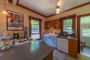 a large kitchen with a counter top and some windows at 1920s Phoenicia Bungalow with Vintage Furnishings, Sauna, Fireplace, & Fenced Backyard in Phoenicia