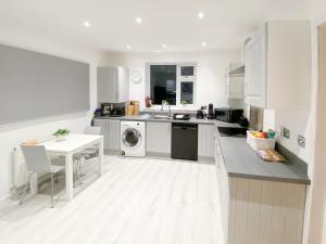 Una cocina con gabinetes blancos, fregadero y lavavajillas. en Newcastle Lodges, en Thornton
