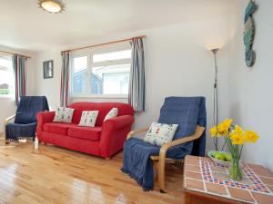 ein Wohnzimmer mit einem roten Sofa und blauen Stühlen in der Unterkunft Lodge 73 - Uk43195 in Saint Merryn