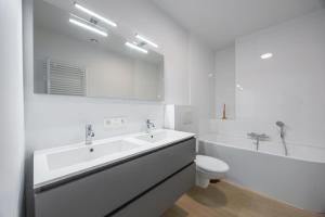 a white bathroom with a tub and a sink and a toilet at Conrad City Stay - 176 in Ostend +35 photos