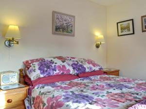 a bedroom with a bed with a floral bedspread at Bridge Cottage in Watchet +5 photos