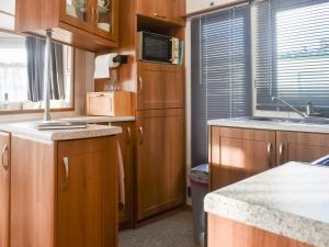 a small kitchen with wooden cabinets and a sink at Cookies Corner in Millom