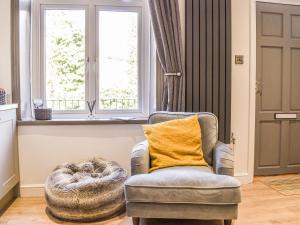 a chair with a yellow pillow in a room with windows at Redmonds Retreat in Chinley