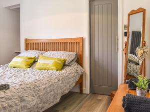 a bedroom with a bed with yellow pillows and a mirror at Redmonds Retreat in Chinley