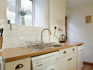 una cucina bianca con lavandino e lavastoviglie di The Tottsie a Bassenthwaite