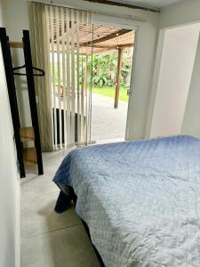 a bedroom with a bed and a sliding glass door at Mini Casa Privativa -Praia do Tombo in Guarujá