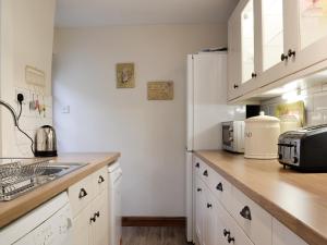 una cucina con mobili bianchi e un frigorifero bianco di The Tottsie a Bassenthwaite Altre 10 foto