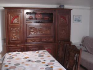 einen großen Holzschrank in einem Wohnzimmer mit einem Tisch in der Unterkunft Appartement Baie du Mont Saint Michel in Cherrueix