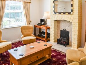 a living room with a fireplace and chairs at Tansey Cottage in Hartlebury