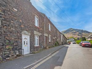 a brick building with a white door on a street at Stybarrow View Cottage in Glenridding