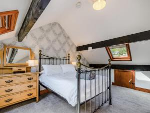 a bedroom with a bed and a dresser and a mirror at Stybarrow View Cottage in Glenridding