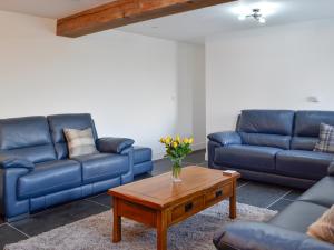 a living room with blue couches and a coffee table at Pistyll Gwyn in Llanwrthwl