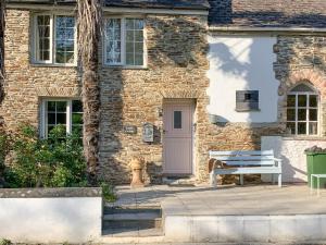 a brick house with a bench and a door at Castle Cottage in Ruan Lanihorne