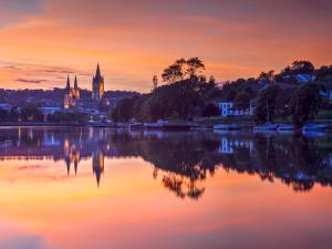 a sunset over a lake with a church in the background at Castle Cottage in Ruan Lanihorne