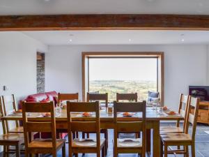 a dining room with a table and chairs and a large window at Pistyll Gwyn in Llanwrthwl
