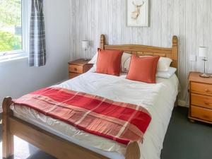 Un dormitorio con una cama grande con almohadas rojas. en Tay Lodge, en Aberfeldy